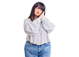 Fototapeta premium Young plus size woman wearing casual clothes sleeping tired dreaming and posing with hands together while smiling with closed eyes.
