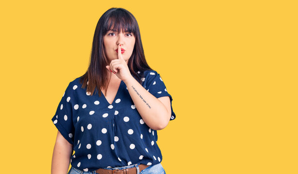 Young plus size woman wearing casual clothes asking to be quiet with finger on lips. silence and secret concept.