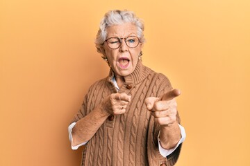 Senior grey-haired woman wearing casual clothes and glasses pointing fingers to camera with happy and funny face. good energy and vibes.