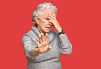 Senior grey-haired woman wearing casual winter sweater covering eyes with hands and doing stop gesture with sad and fear expression. embarrassed and negative concept.
