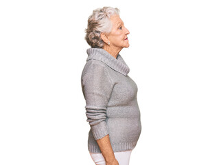 Senior grey-haired woman wearing casual winter sweater looking to side, relax profile pose with...