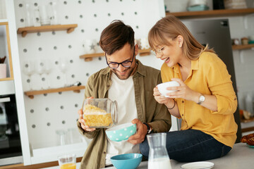 Young couple eating breakfast at home. Loving couple enjoying in the kitchen.