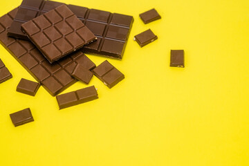 Tiles and milk chocolate slices lie on a yellow background