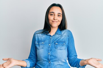 Young hispanic woman wearing casual denim jacket winking looking at the camera with sexy...