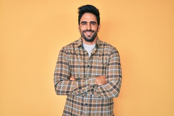 Handsome hispanic man with beard wearing casual clothes happy face smiling with crossed arms looking at the camera. positive person.
