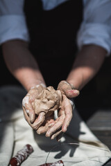 Female potter shaping piece of clay at the table. Woman making ceramic item. Pottery working, handmade and creative skills at arts studio.