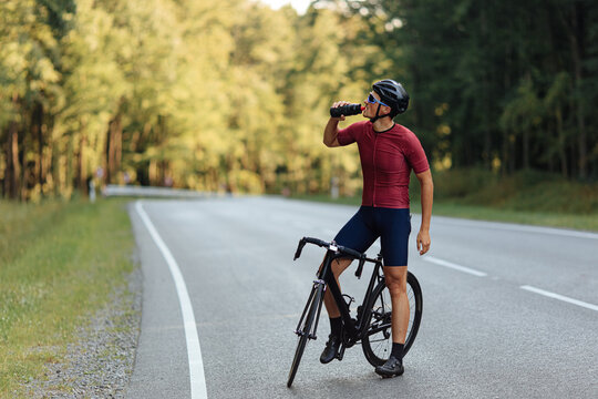 Young man sitting on bike and drinking fresh water