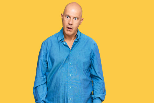 Middle age bald man wearing casual clothes in shock face, looking skeptical and sarcastic, surprised with open mouth