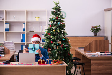 Young male employee celebrating Christmas at workplace