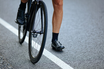 Fototapeta premium Close up of male muscular legs sitting on bike outdoors