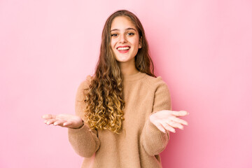 Young caucasian woman makes scale with arms, feels happy and confident.