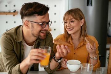 Young couple making sandwich at home. Loving couple drinking coffee while preparing the breakfast.