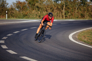 Young sportsman in helmet biking on asphalt road