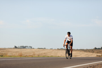 Sportsman in helmet riding bike among countryside