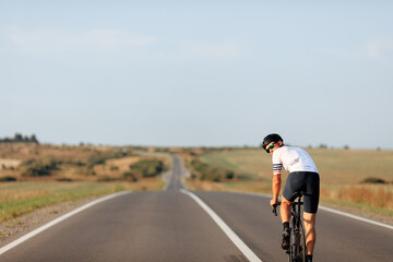 Obraz premium Man in eyewear and helmet cycling in the middle of road