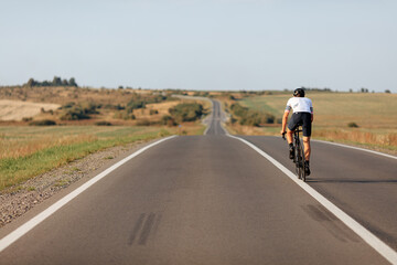 Sporty man cycling on white separation line of road