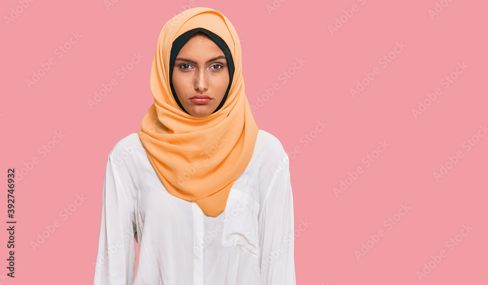 Poster Young brunette woman wearing traditional islamic hijab scarf with serious expression on face. simple and natural looking at the camera.