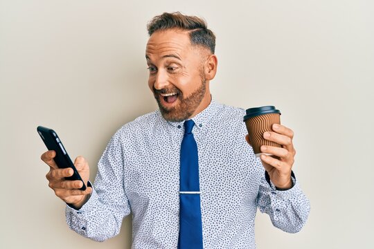 Handsome middle age business man using smartphone and drinking a cup of coffee celebrating crazy and amazed for success with open eyes screaming excited.