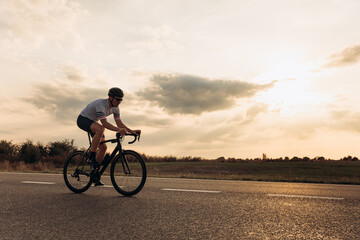 Athletic man riding bike on asphalt road
