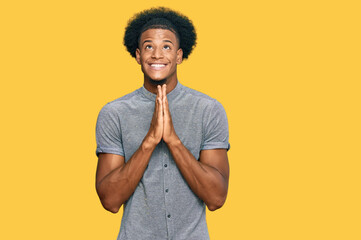 African american man with afro hair wearing casual clothes begging and praying with hands together...