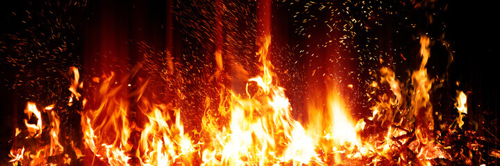 Burning red hot sparks rise from large fire in the night. Fire flames sparks background. Abstract...