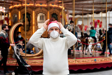 Coronavirus and Christmas mood in Europe. man in protective medical mask and Santa hat in historic center of Florence Italy. Covid-19 quarantine in Europe  Italy, France, Germany, Spain