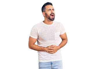 Young hispanic man wearing casual clothes with hand on stomach because nausea, painful disease feeling unwell. ache concept.