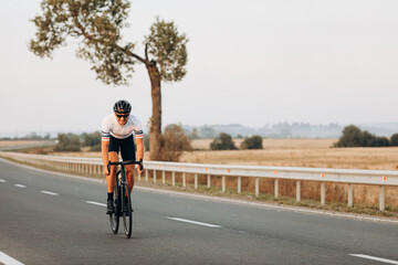 Cheerful man cycling on paved road among countryside