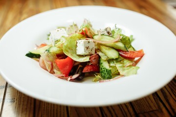 Greek salad on wooden background top view. Space for text. Healthy food
