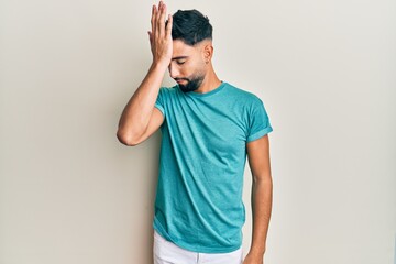 Young man with beard wearing casual clothes surprised with hand on head for mistake, remember error. forgot, bad memory concept.