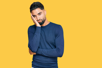 Young man with beard wearing casual blue winter sweater thinking looking tired and bored with depression problems with crossed arms.