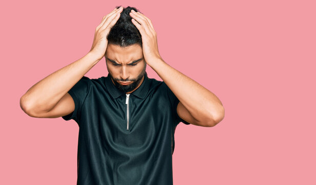 Young man with beard wearing sportswear suffering from headache desperate and stressed because pain and migraine. hands on head.