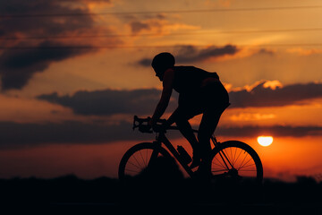 Young sportsman in silhouette riding bike outdoors
