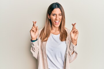 Brunette young woman doing fingers crossed gesture winking looking at the camera with sexy...