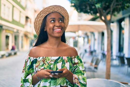 Young african american tourist woman on vacation smiling happy using smartphone at the city.