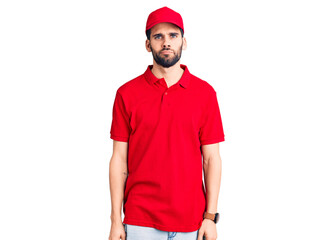 Young handsome man with beard wearing delivery uniform looking sleepy and tired, exhausted for fatigue and hangover, lazy eyes in the morning.