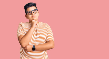Obraz premium Little boy kid wearing casual clothes and glasses with hand on chin thinking about question, pensive expression. smiling with thoughtful face. doubt concept.