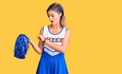Young beautiful woman wearing cheerleader uniform looking at the watch time worried, afraid of...