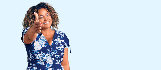 Young african american plus size woman wearing casual clothes smiling friendly offering handshake as greeting and welcoming. successful business.