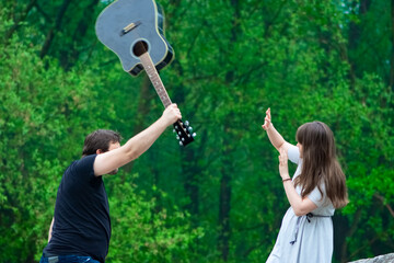 Man hitting the woman by guitar outdoor