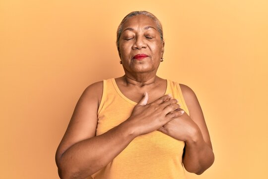 Senior african american woman wearing casual style with sleeveless shirt smiling with hands on chest, eyes closed with grateful gesture on face. health concept.