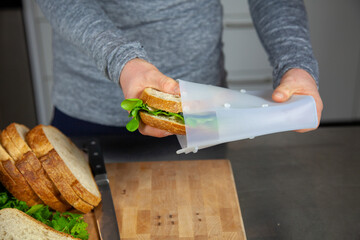 A women prepares lunch and puts a sandwich into a food-grade silicone bag as part of a zero-waste...