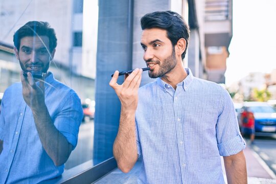 Young hispanic man smiling happy sending audio message using smartphone at city.