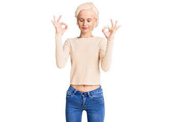 Young blonde woman wearing casual clothes relaxed and smiling with eyes closed doing meditation gesture with fingers. yoga concept.