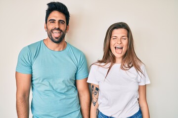 Fototapeta premium Beautiful young couple of boyfriend and girlfriend together sticking tongue out happy with funny expression. emotion concept.
