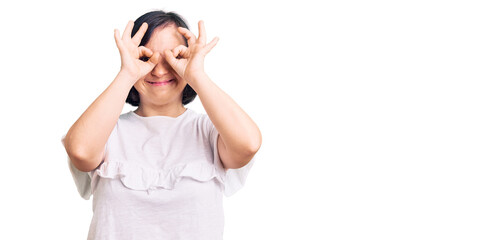 Fototapeta na wymiar Brunette woman with down syndrome wearing casual white tshirt doing ok gesture like binoculars sticking tongue out, eyes looking through fingers. crazy expression.