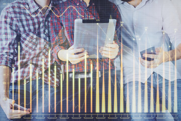 Double exposure of forex graph drawing and man and woman working together holding and using a...