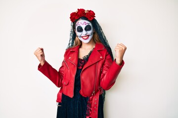 Woman wearing day of the dead costume over white very happy and excited doing winner gesture with arms raised, smiling and screaming for success. celebration concept.