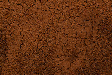 Dry cracked coffee ground close up. Abstract brown textured backdrop with cracks and grains.