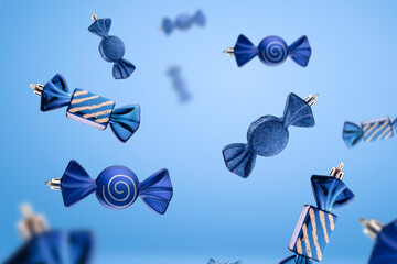 Blue candies fall from the sky. New year's Christmas glass toys on a blue pleasant minimalist...